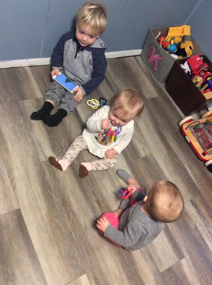 Three children playing on a wooden floor