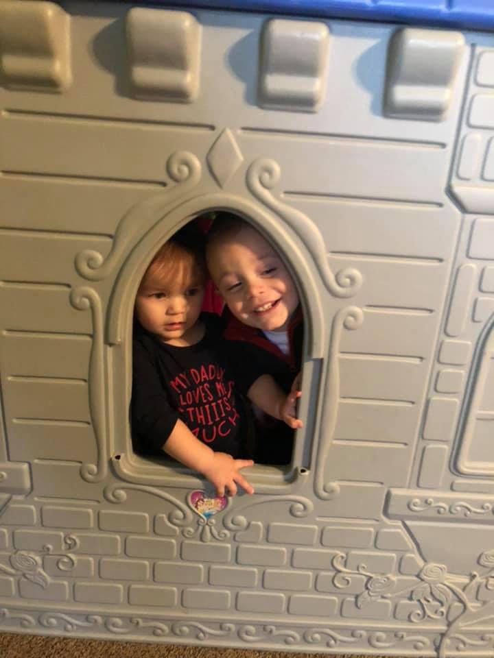 Two children looking out of a playhouse window