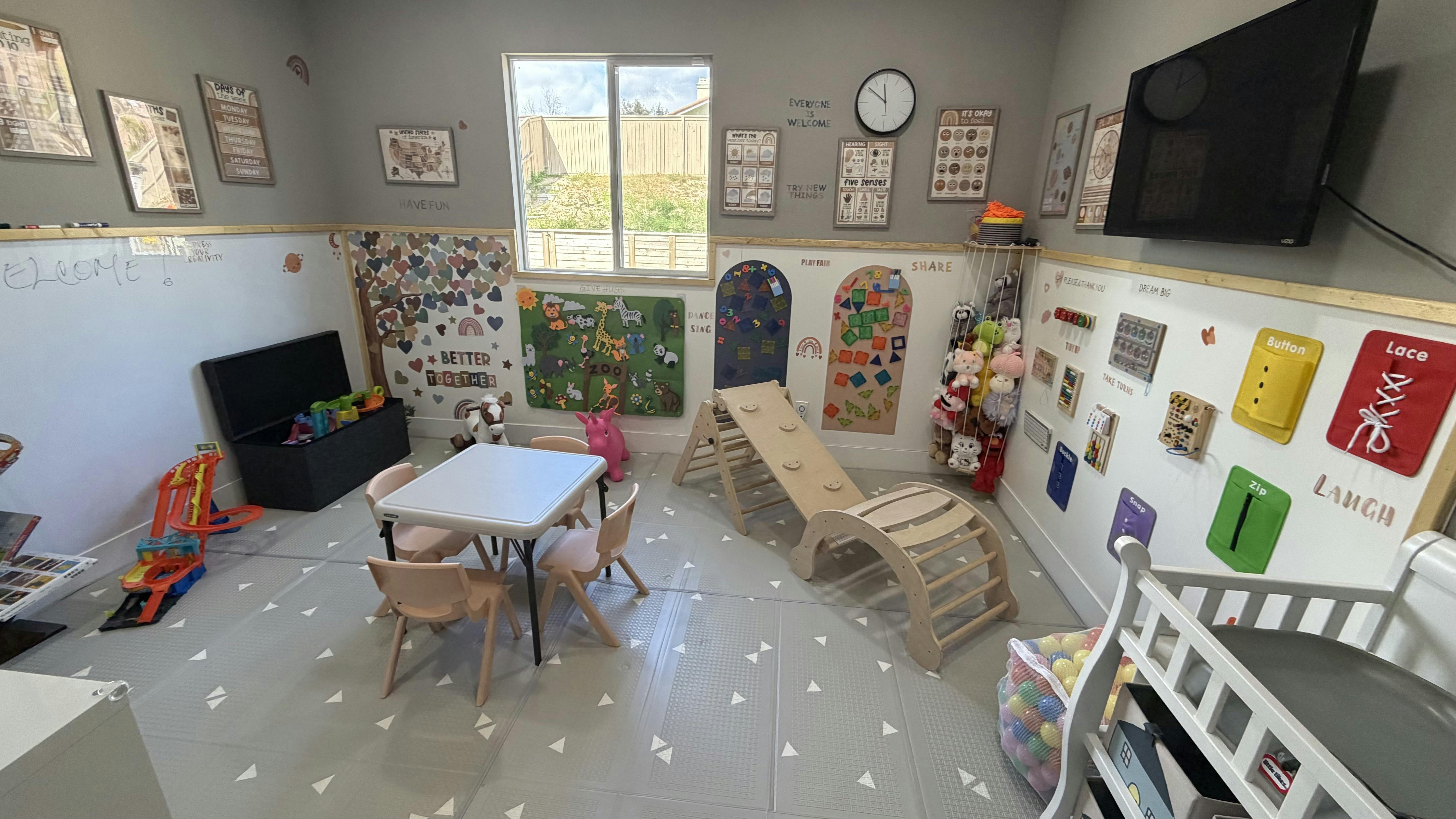 Children's playroom with small table and chairs, climbing structure, and wall decorations