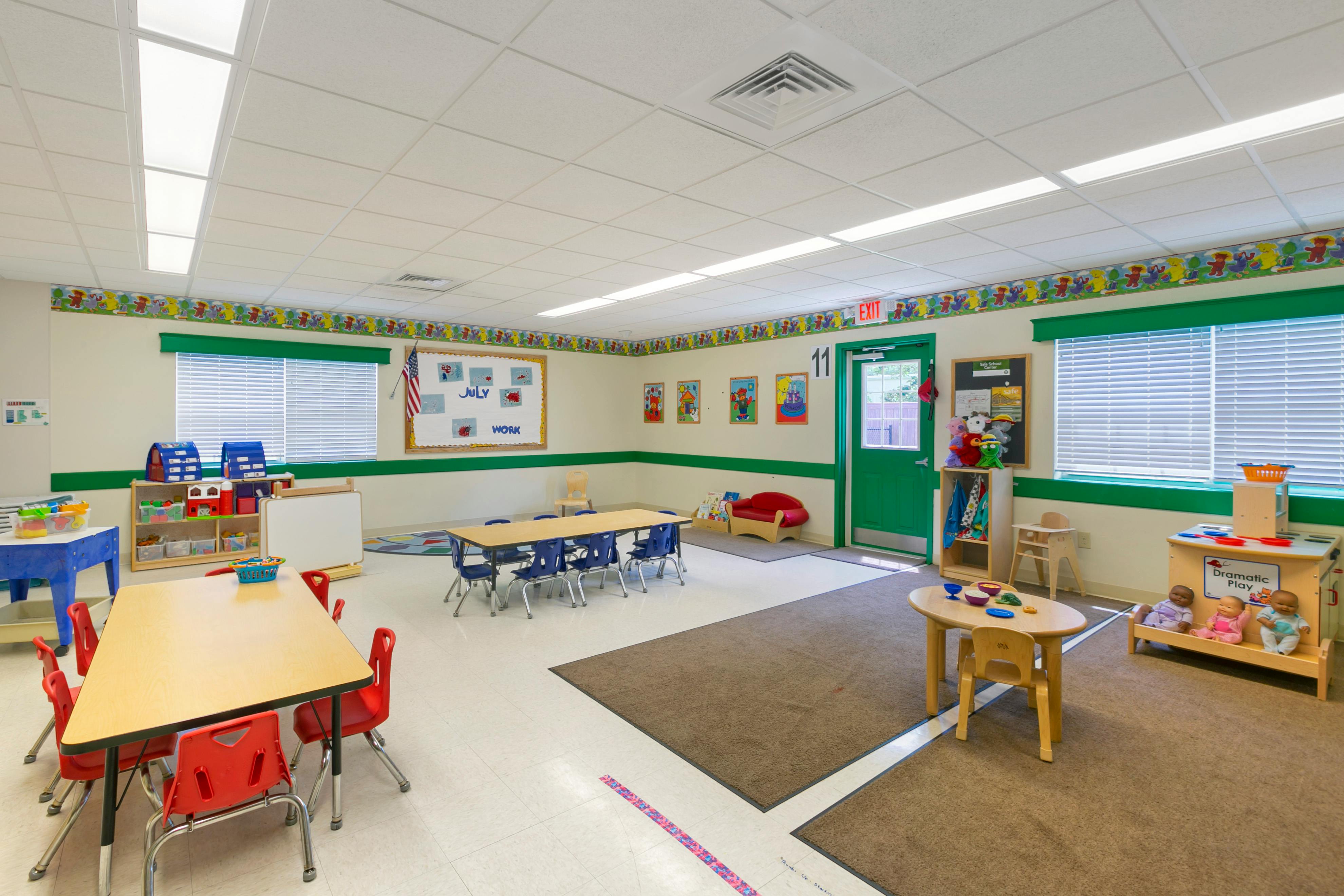 Classroom with child-sized tables and chairs, shelves with toys, and bulletin boards
