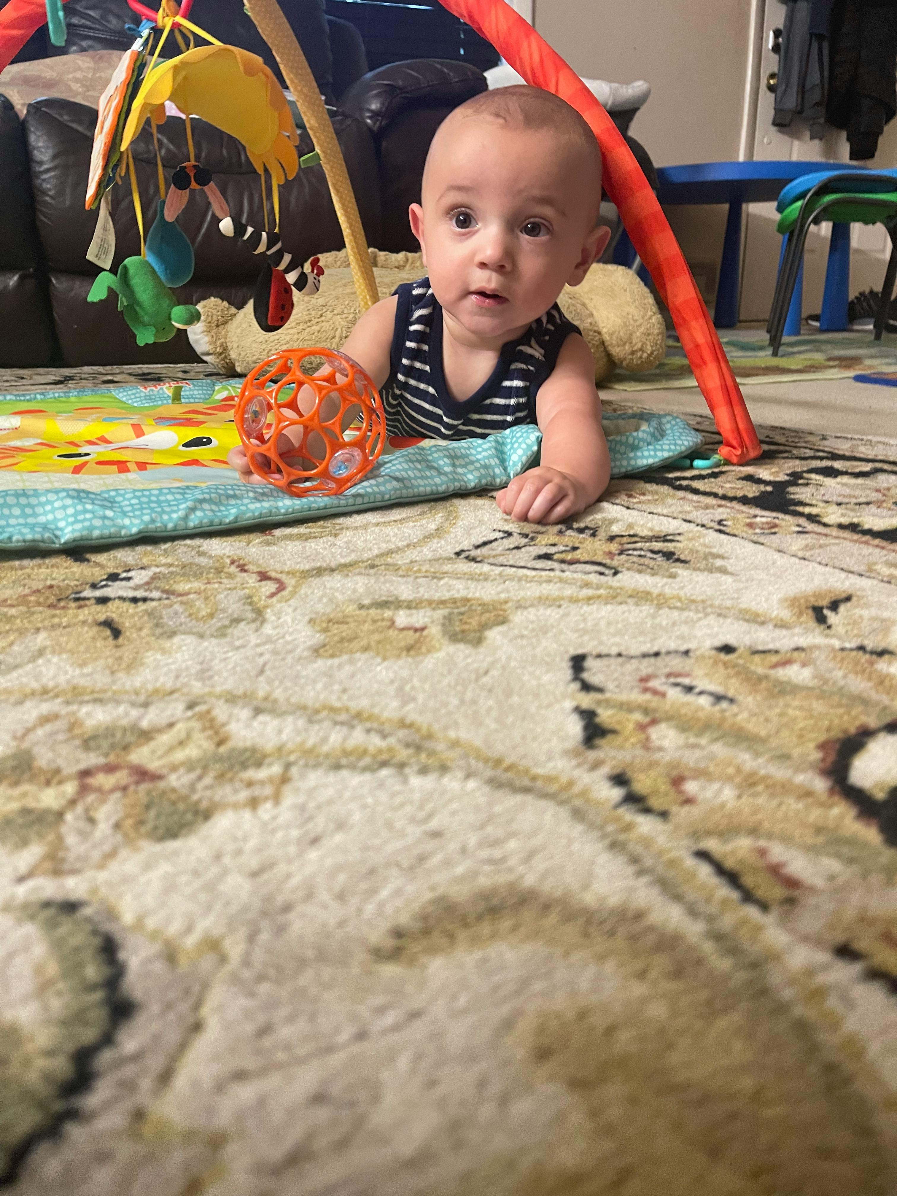 Child on a playmat with an orange ball