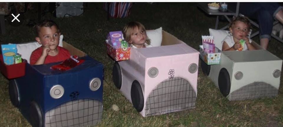 Three children sitting in cardboard box cars