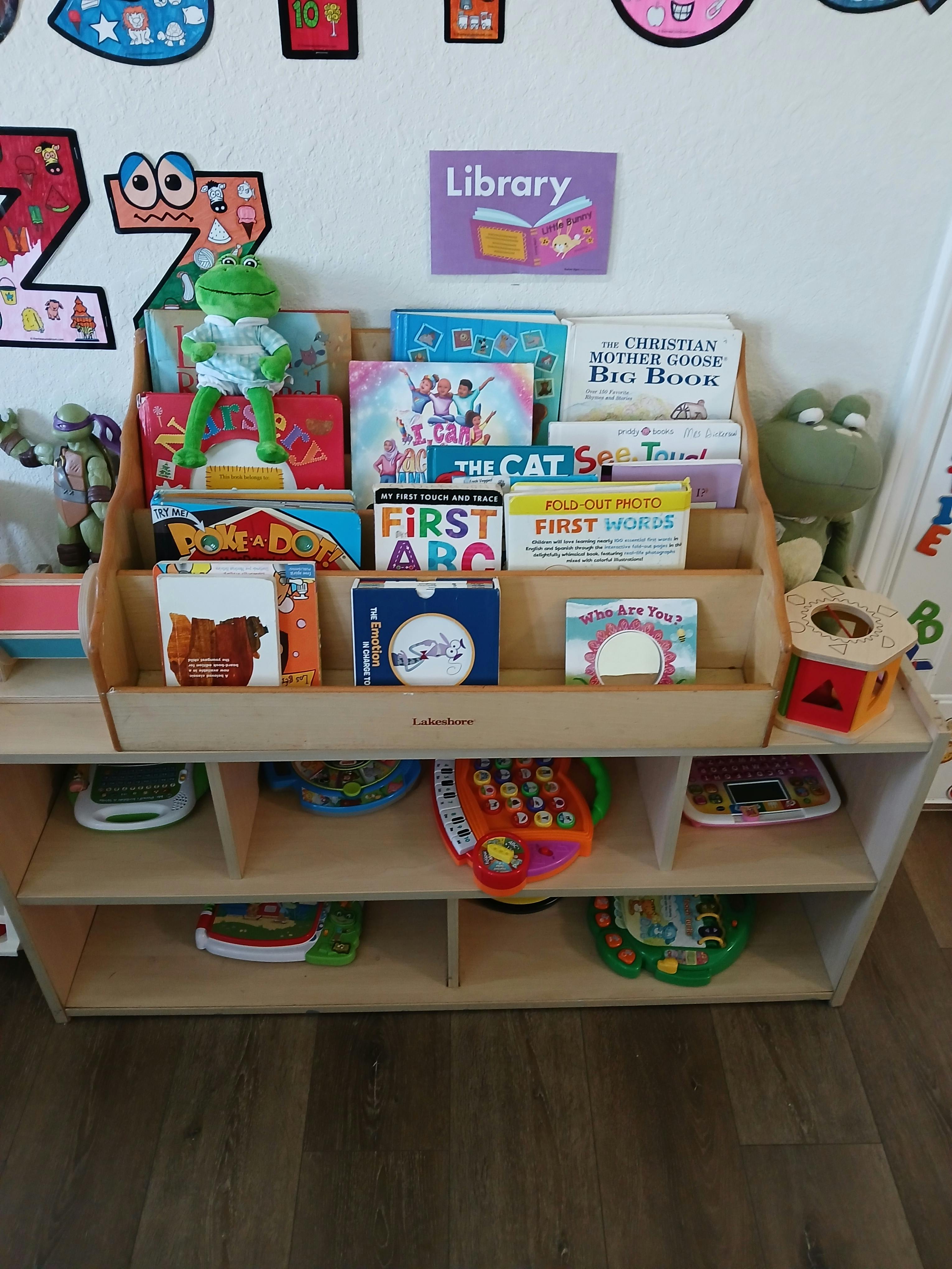 Children's book display with a frog toy on top