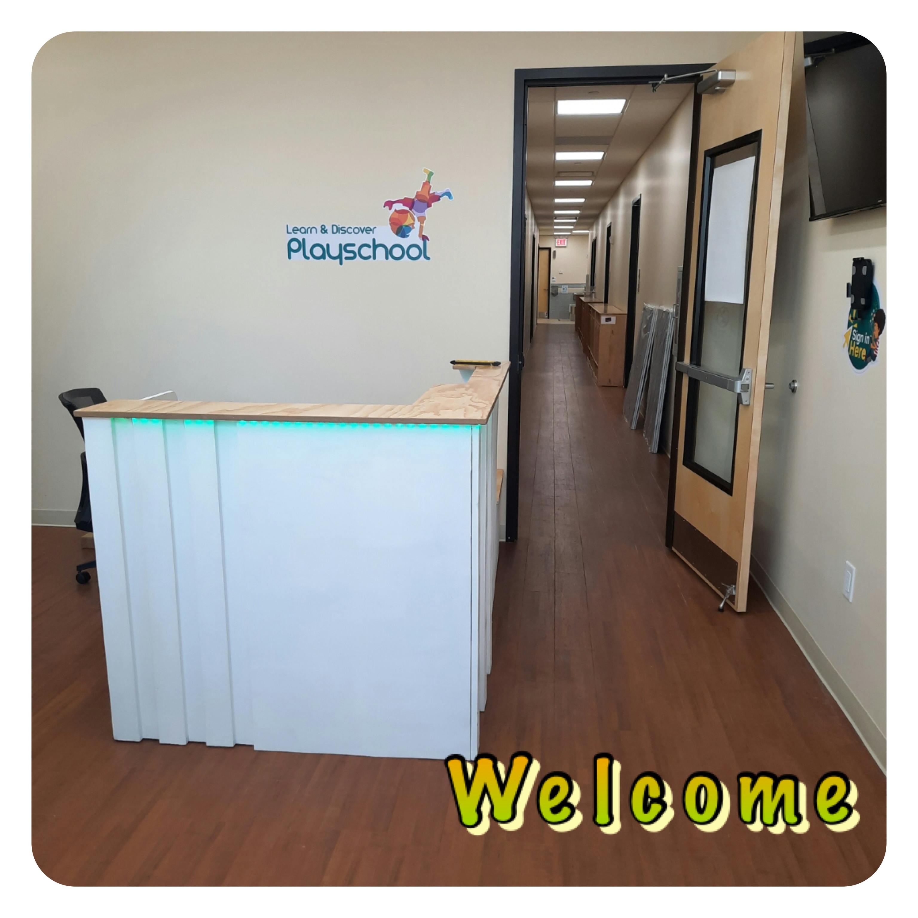 Reception desk with "Learn & Discover Playschool" logo on wall