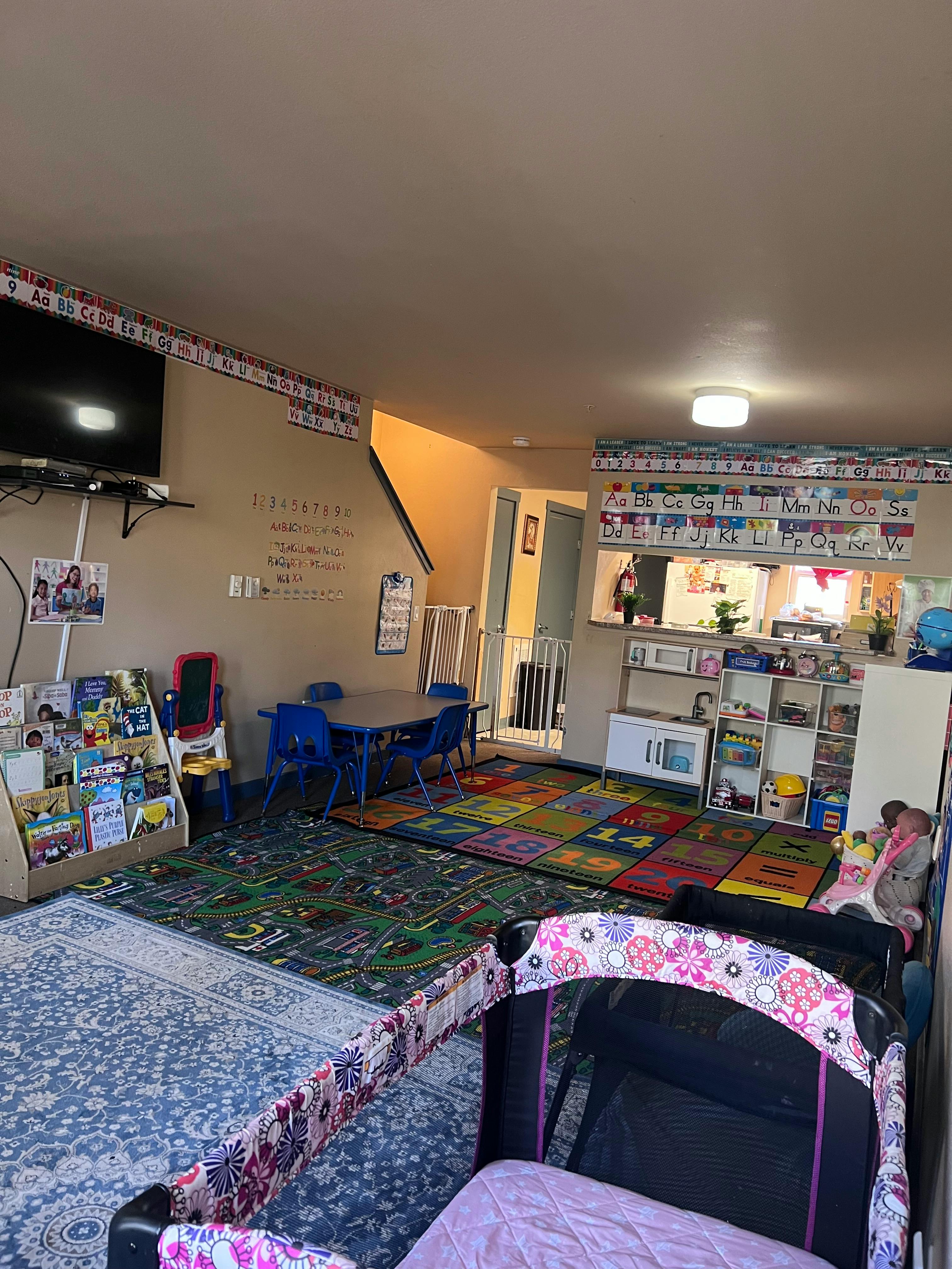 Childcare room with play mats, small tables, and a crib
