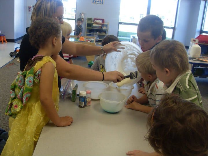 Adult and children gathered around a table mixing ingredients in a bowl
