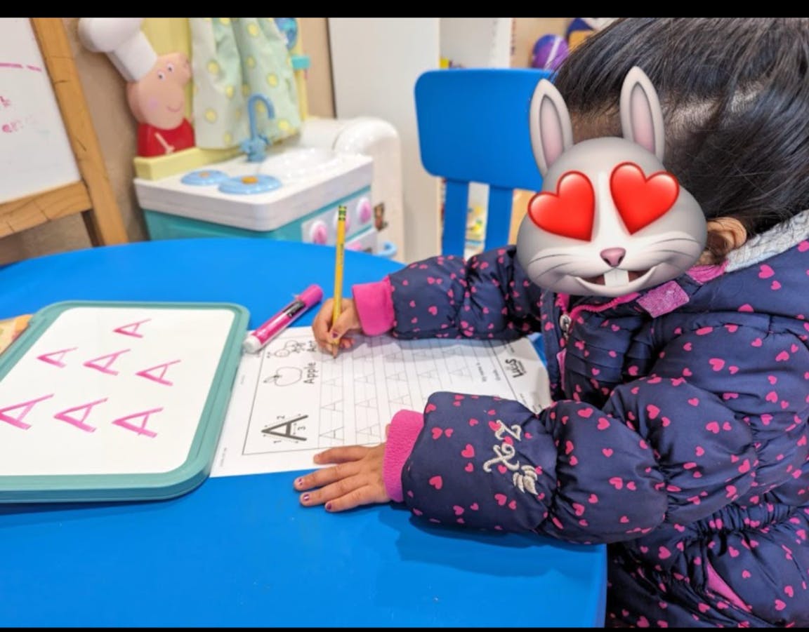Child writing on a worksheet at a blue table