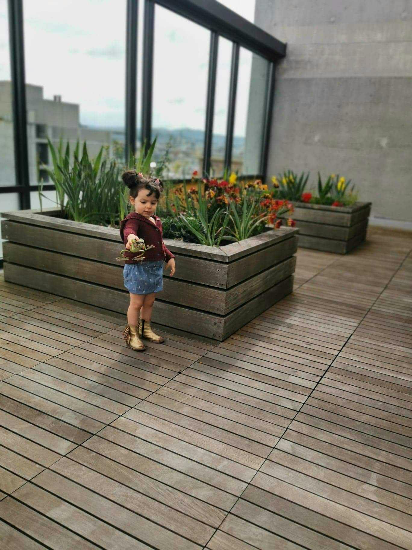 Child standing on a wooden deck holding a small object