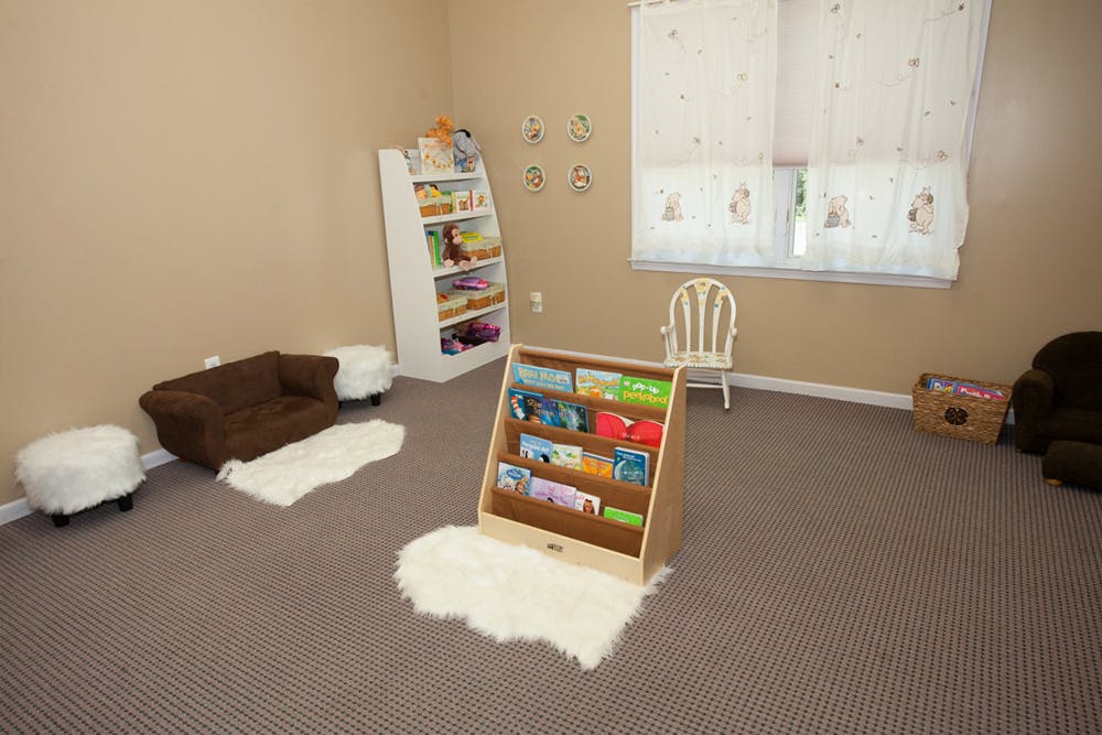 Room with small furniture, bookshelves, and window