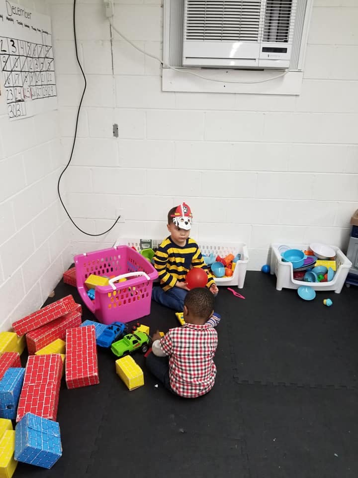 Two children playing with toys on a black mat