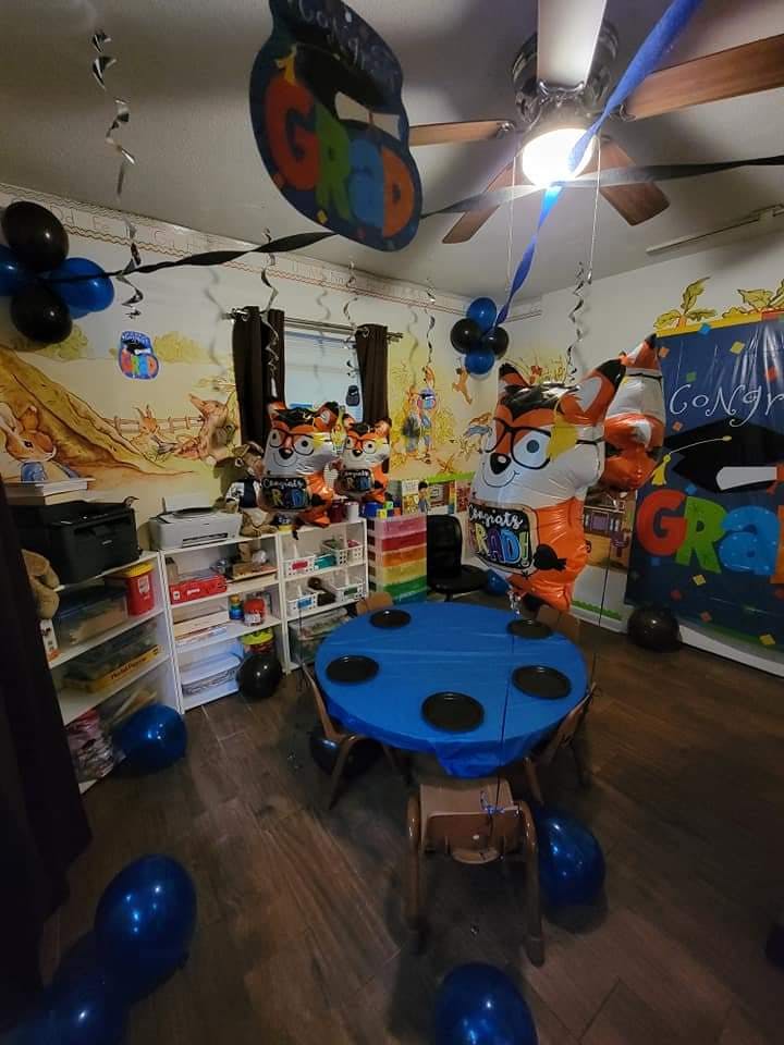 Room decorated with balloons and large character cutouts, a blue table in the center