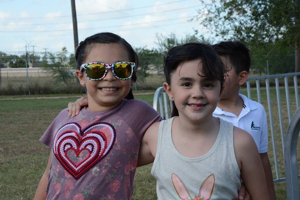 Two children standing together, one wearing sunglasses