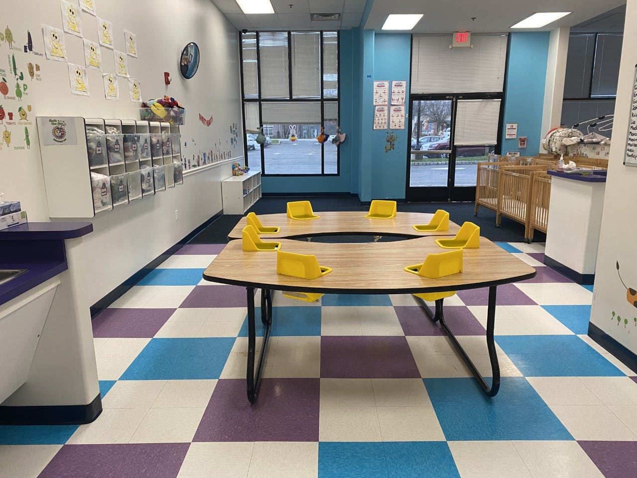 Classroom with a large table and yellow chairs on a checkered floor