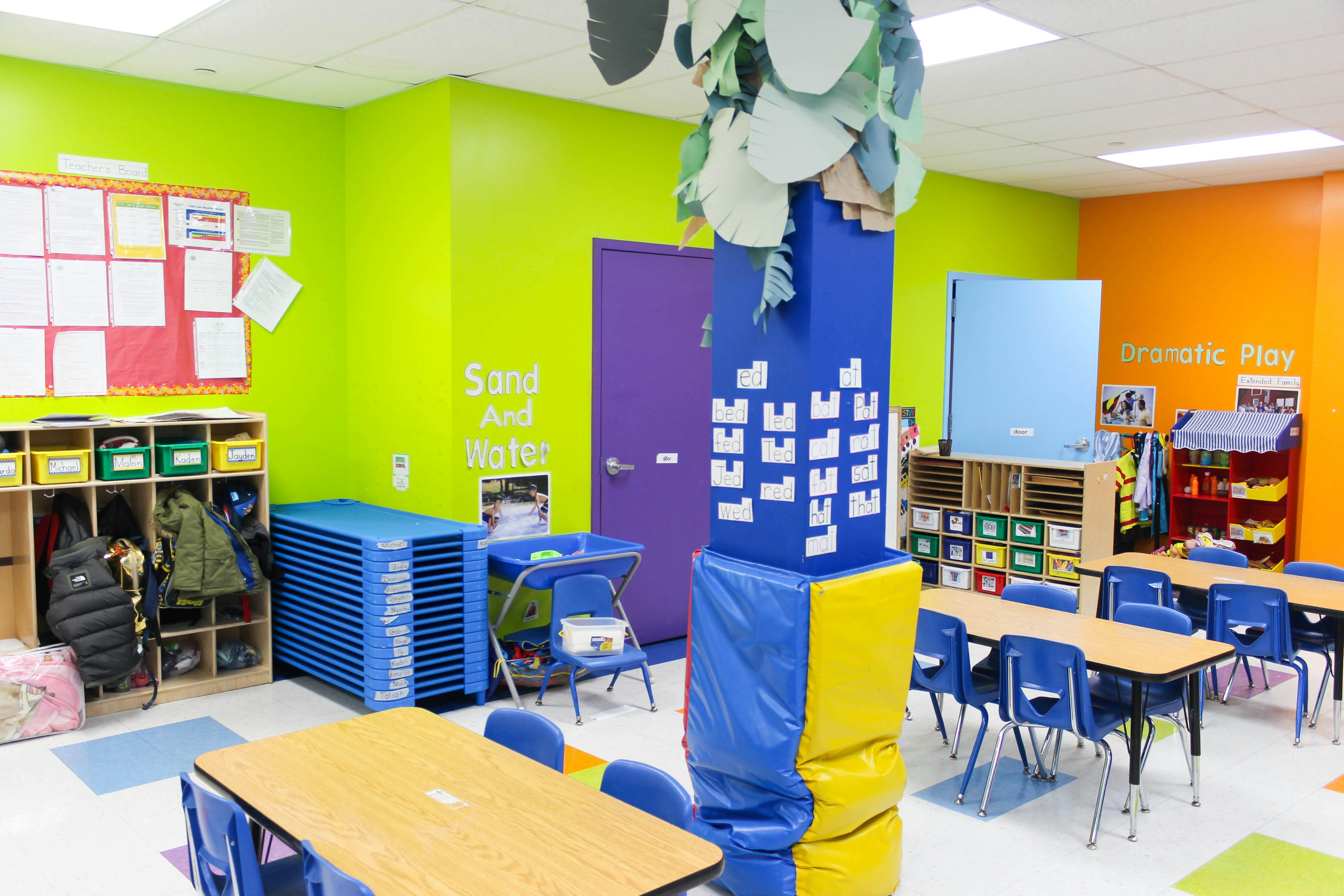 Colorful classroom with tables, chairs, storage, and a padded pillar
