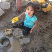 Child playing in sand with toys