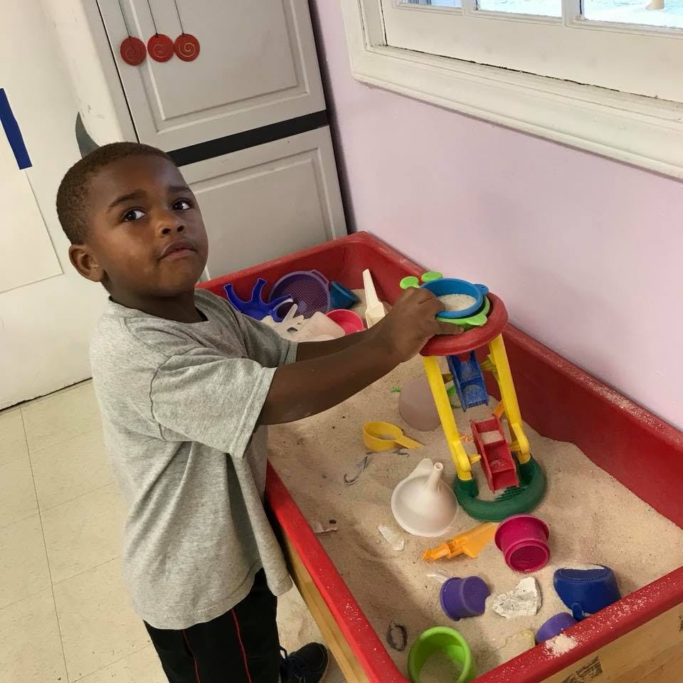 Child playing with a sand and water table toy