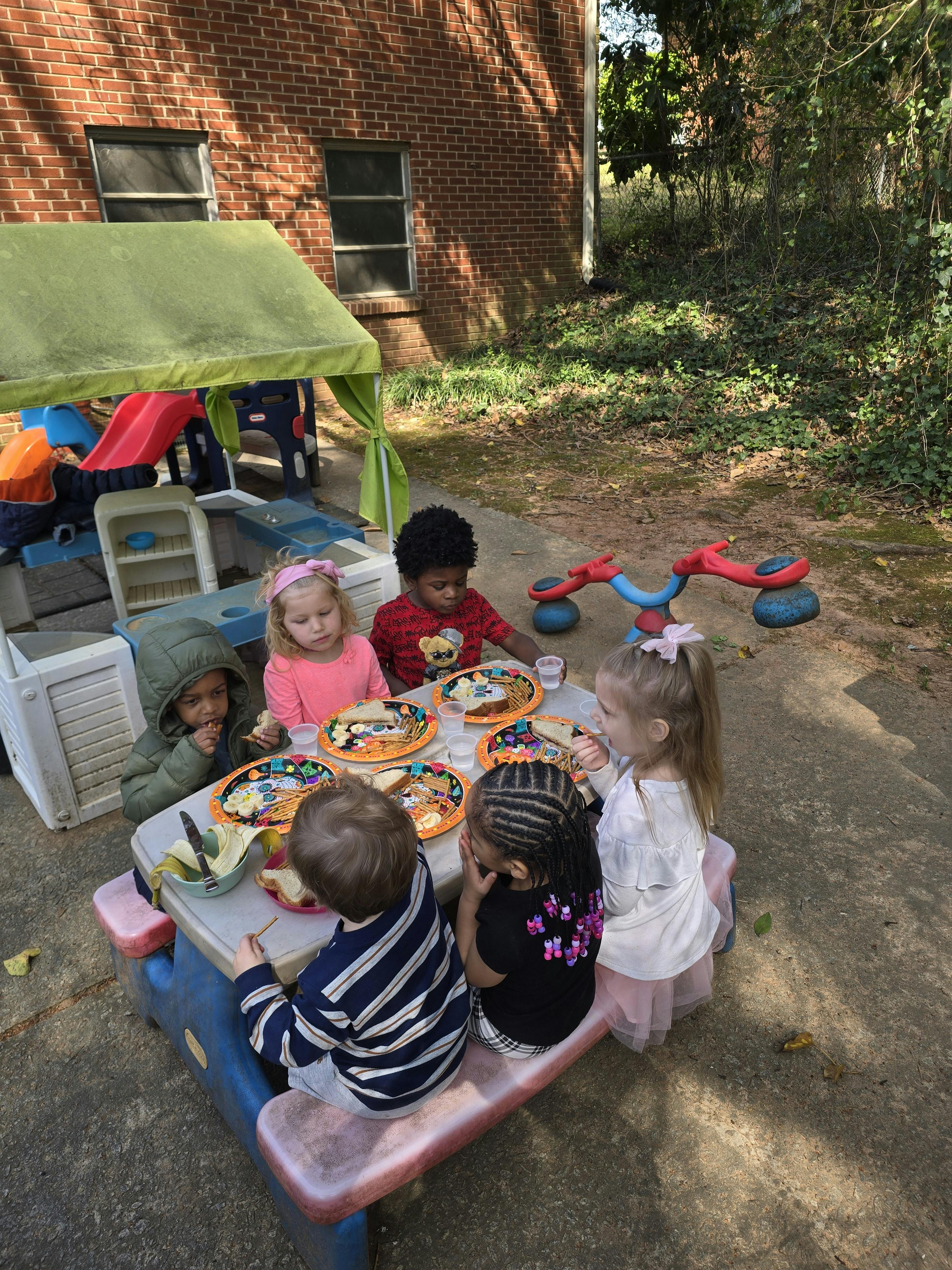 Children eating at a picnic table outdoors