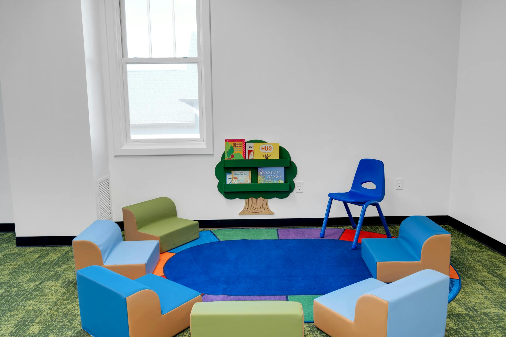 Children's reading area with colorful chairs and a tree-shaped bookshelf