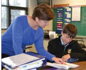 Adult and teen looking at a book in a classroom