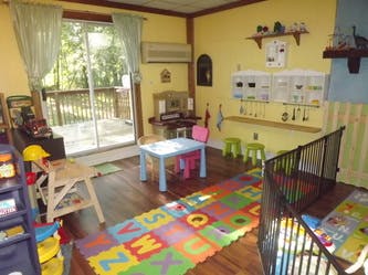 Playroom with colorful alphabet mat, small table and chairs, and crib