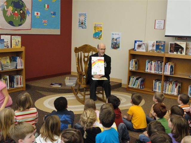 Person reading a book to a group of children in a classroom