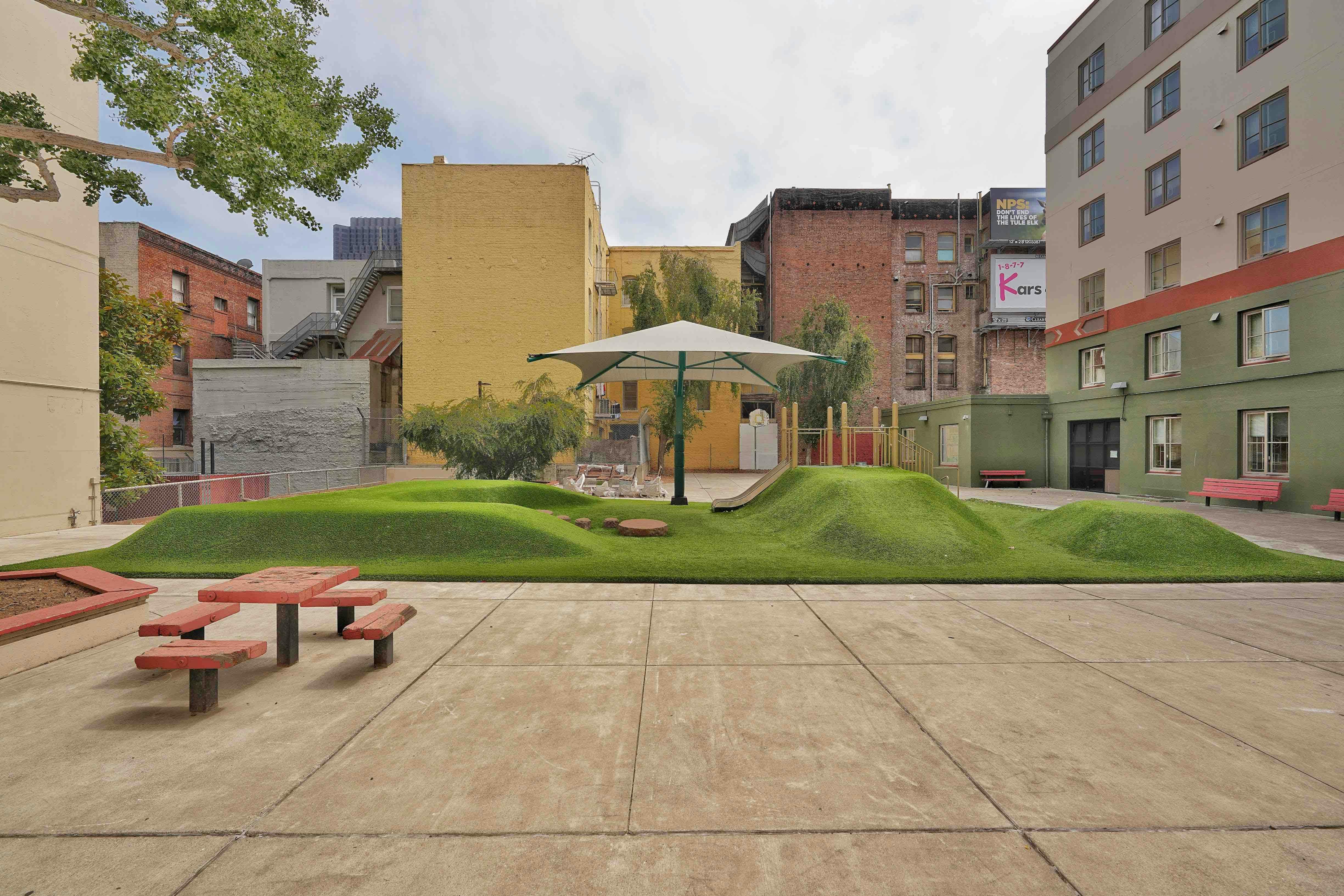 Urban park with artificial grass mounds and a shade structure