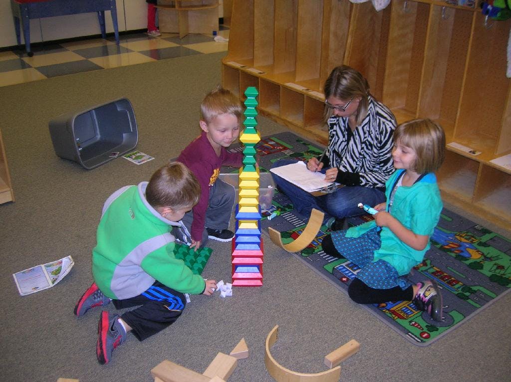 Adult and three children playing with blocks on the floor