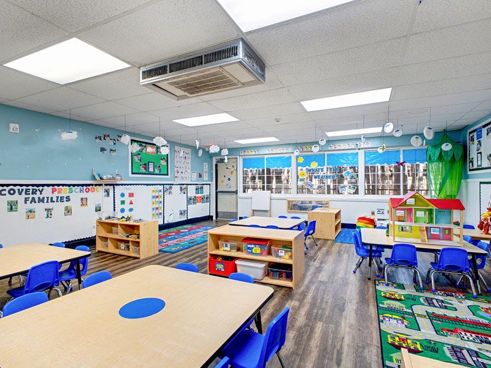 Empty preschool classroom with tables, chairs, and colorful decorations