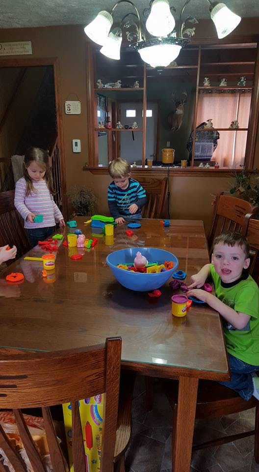 Three children playing with colorful toys at a table