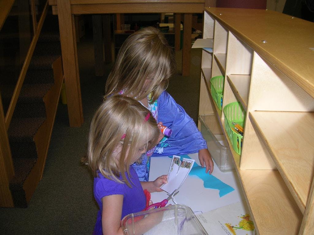 Two children looking at papers and crafts in a classroom