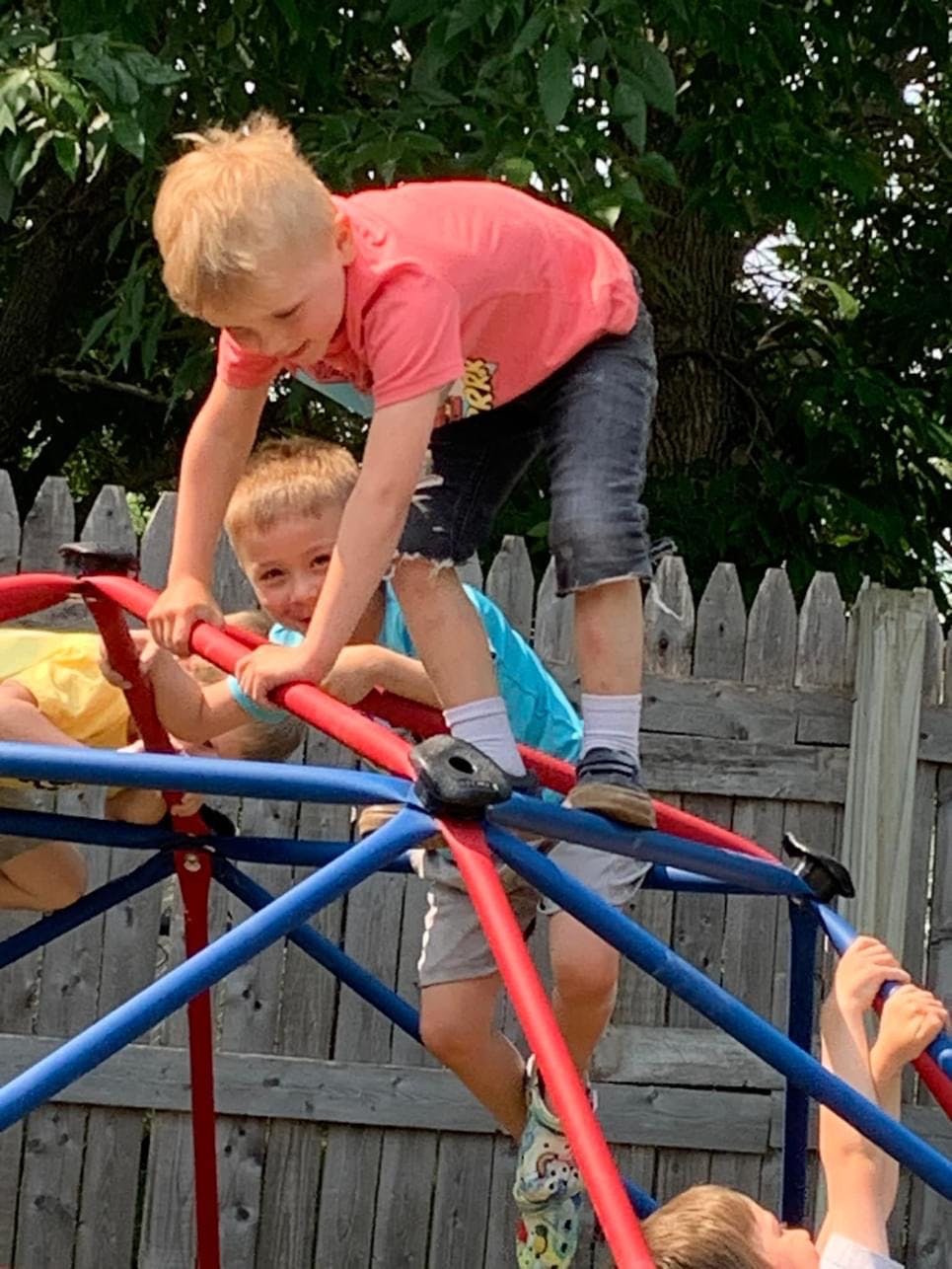 Two children climbing on a red and blue jungle gym