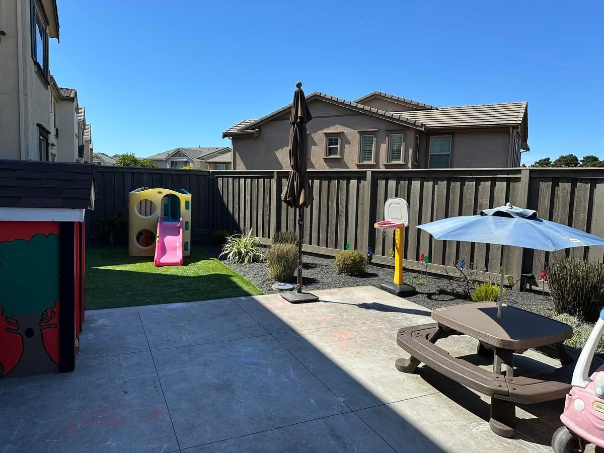 Backyard with playhouse, slide, picnic table, and umbrellas