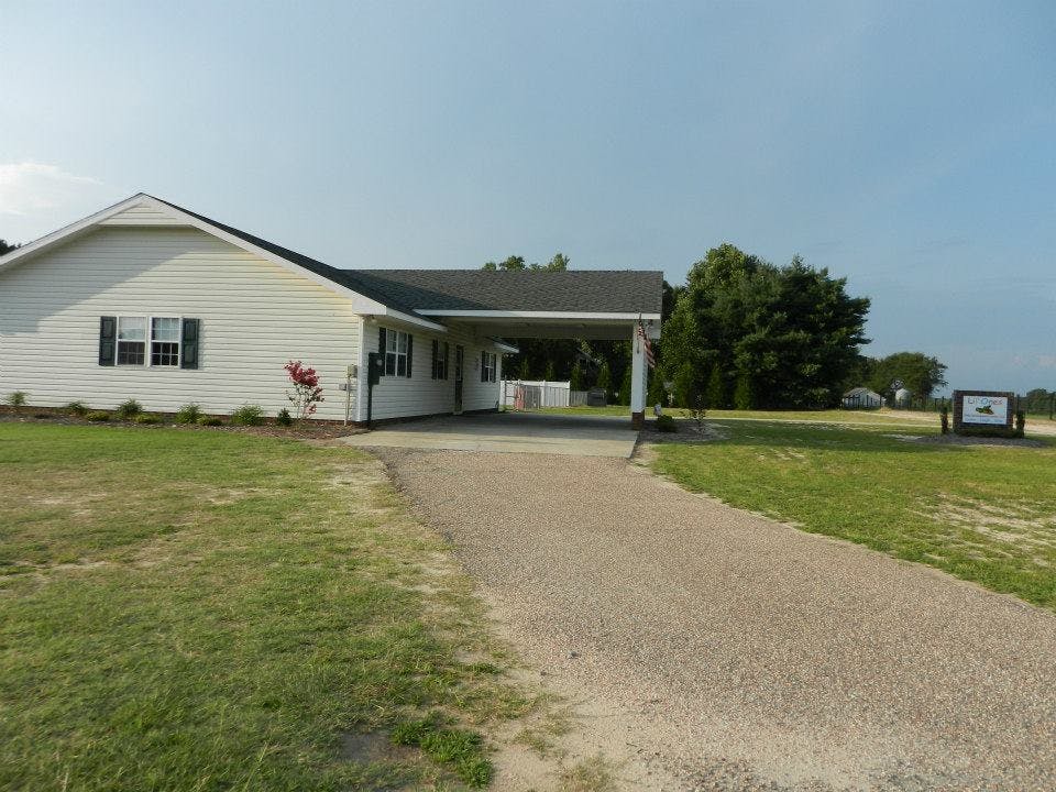 White house with a carport and a gravel driveway