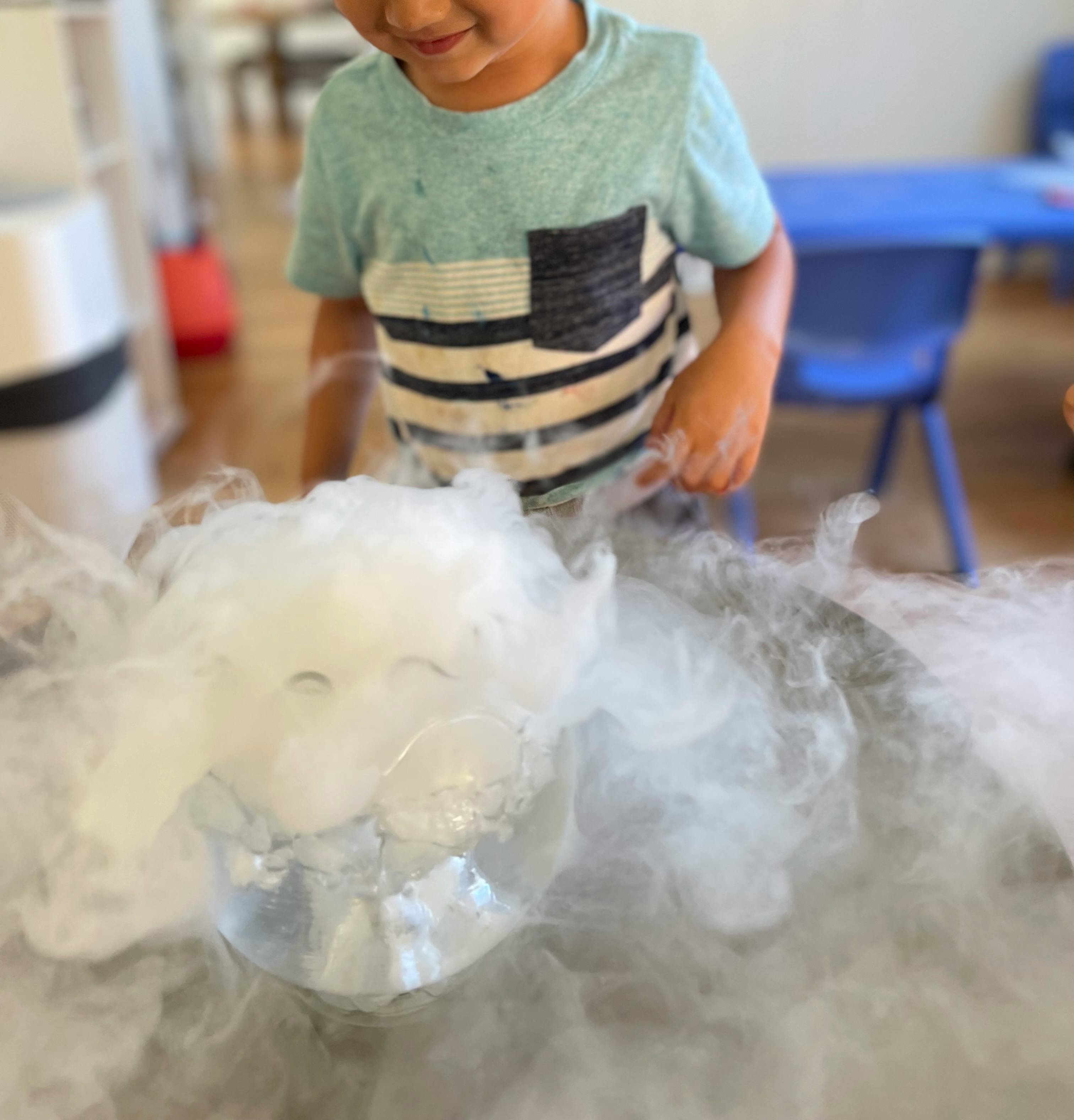 Child looking at a bowl of dry ice with vapor rising