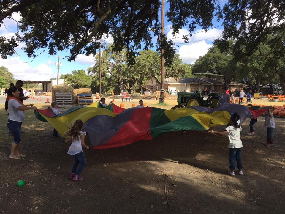 People and children playing with a large colorful parachute outdoors