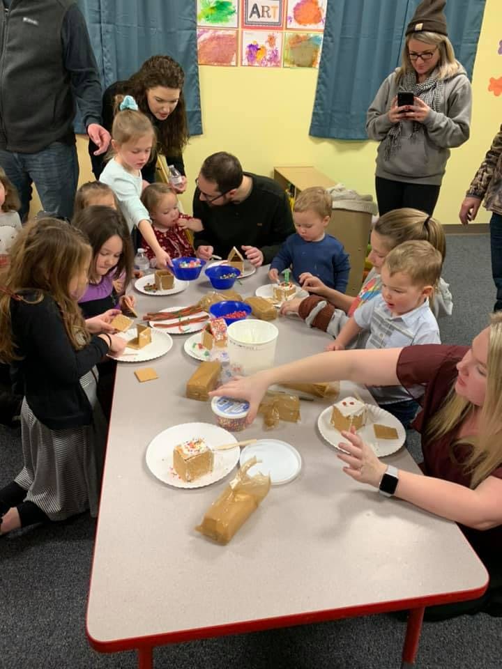 Adults and children decorating small cakes at a table