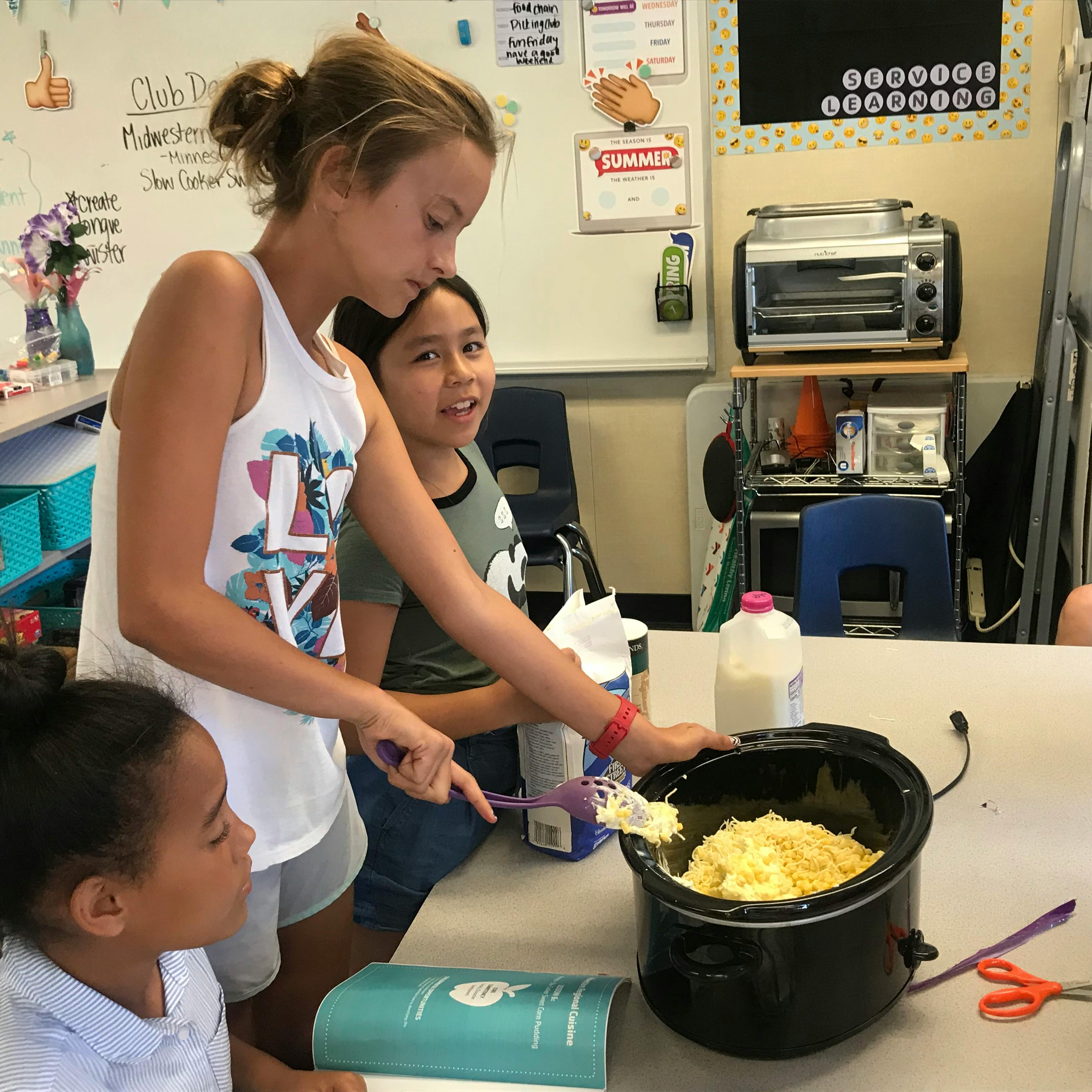 Teen and two children cooking in a classroom