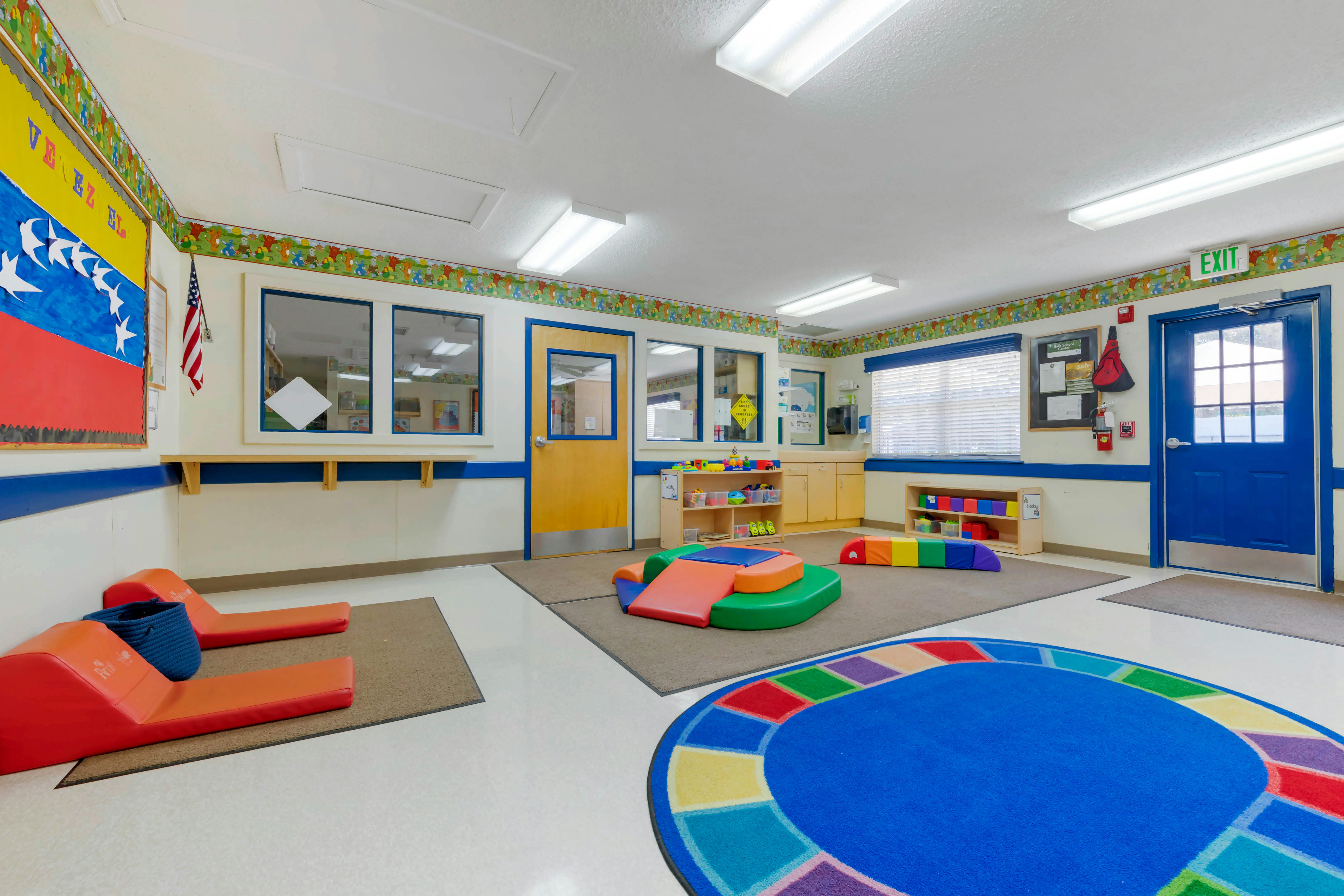 An empty early childhood classroom with colorful floor mats and learning materials