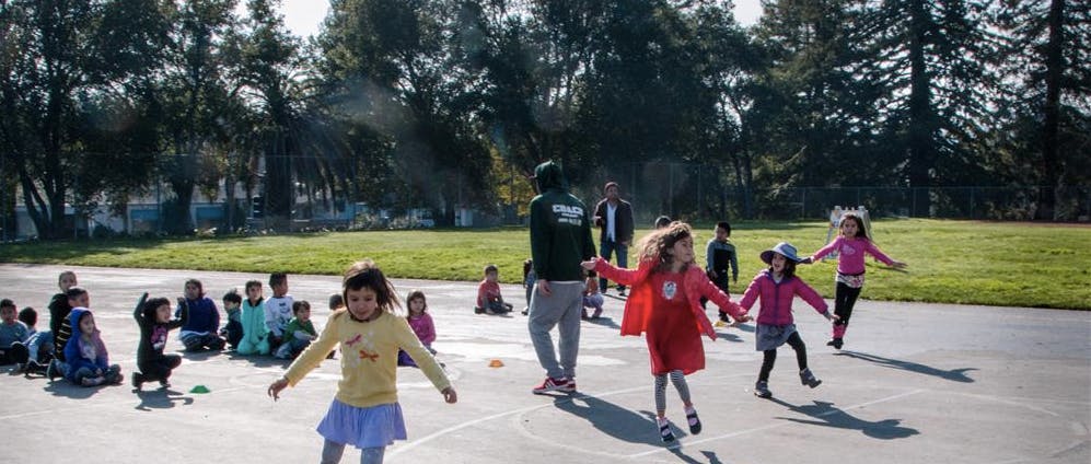 Children playing outdoors with an adult supervising