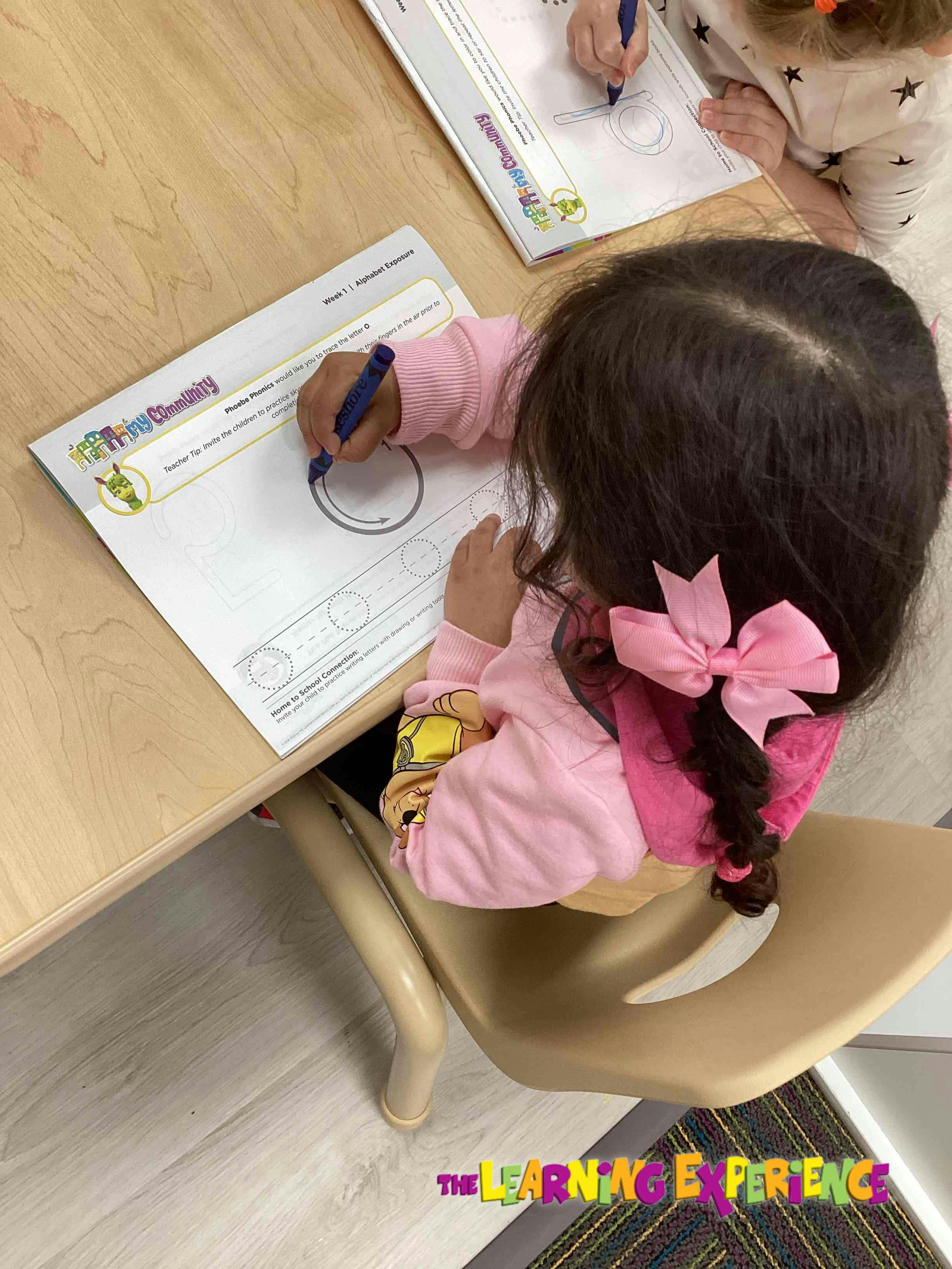 Child drawing circles on a worksheet at a table