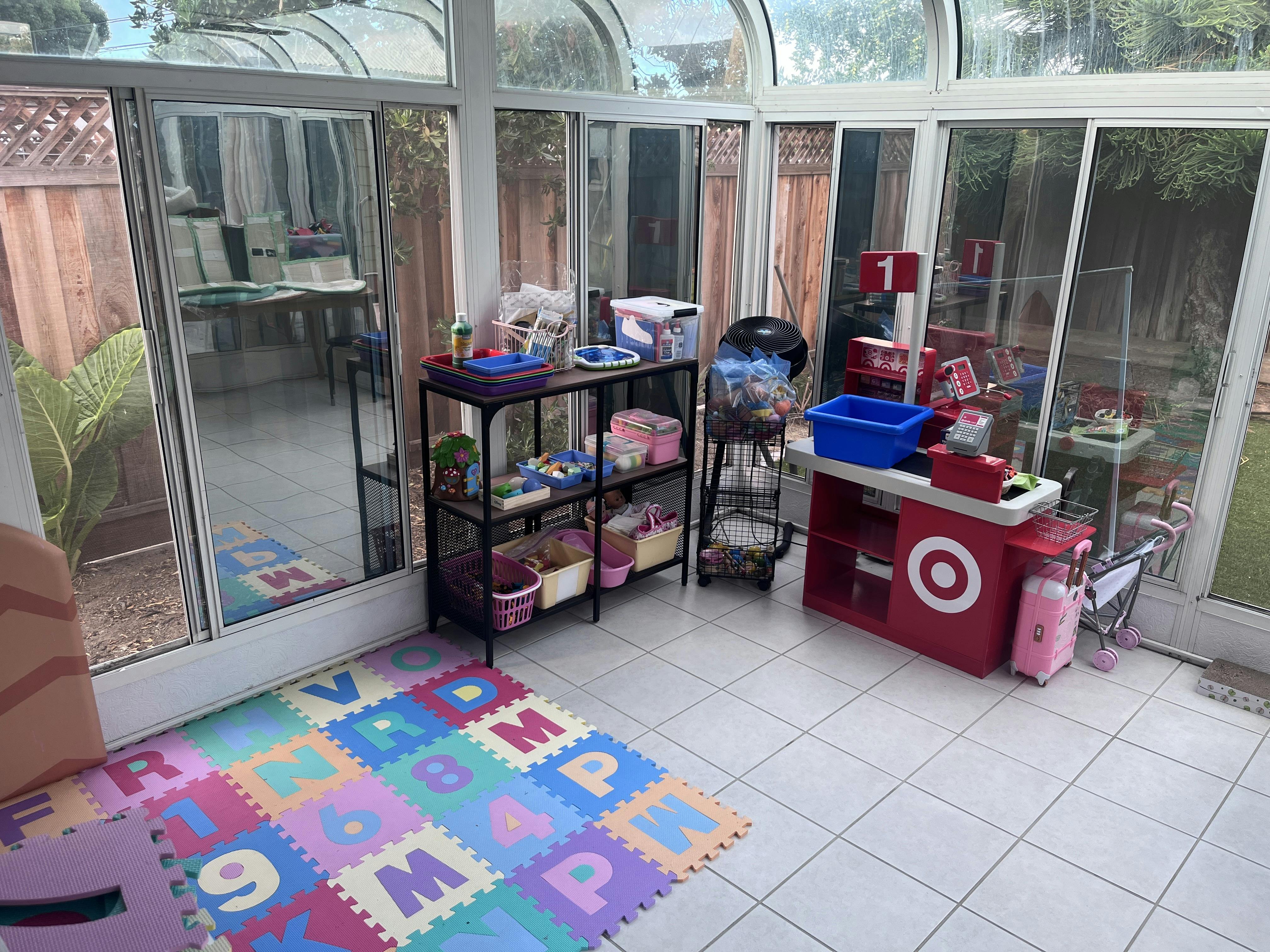 Playroom with a toy checkout stand, shelving unit, and colorful foam floor tiles