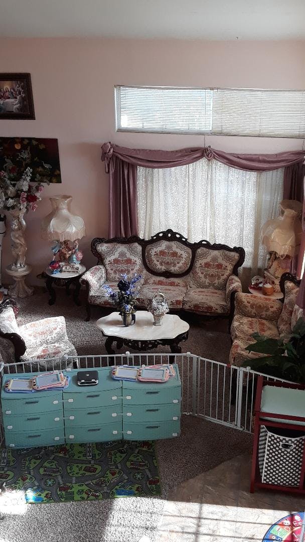Living room with ornate patterned furniture, a playpen, and toys