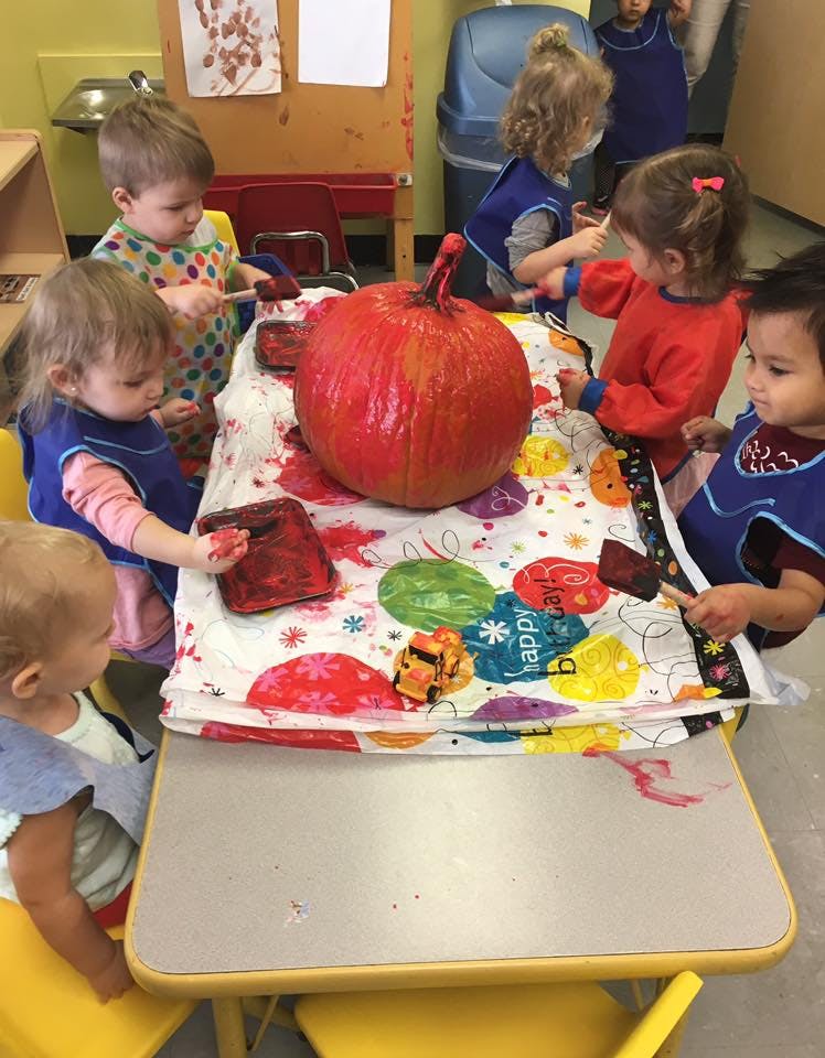 Children painting a pumpkin in a classroom