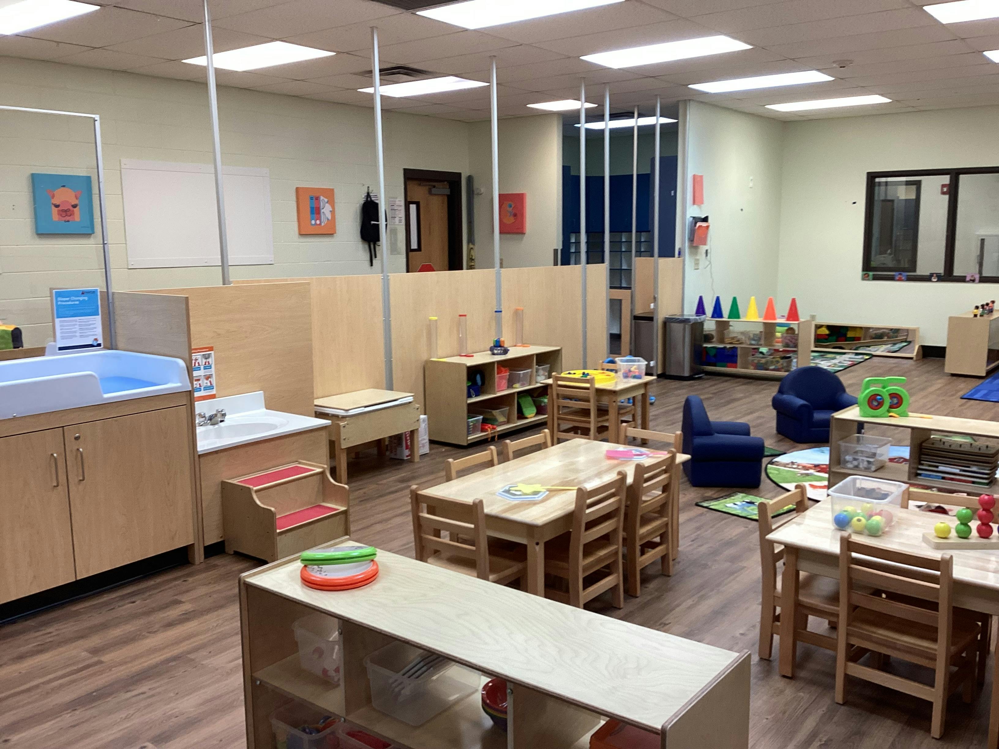 An empty early childhood classroom with play areas and tables