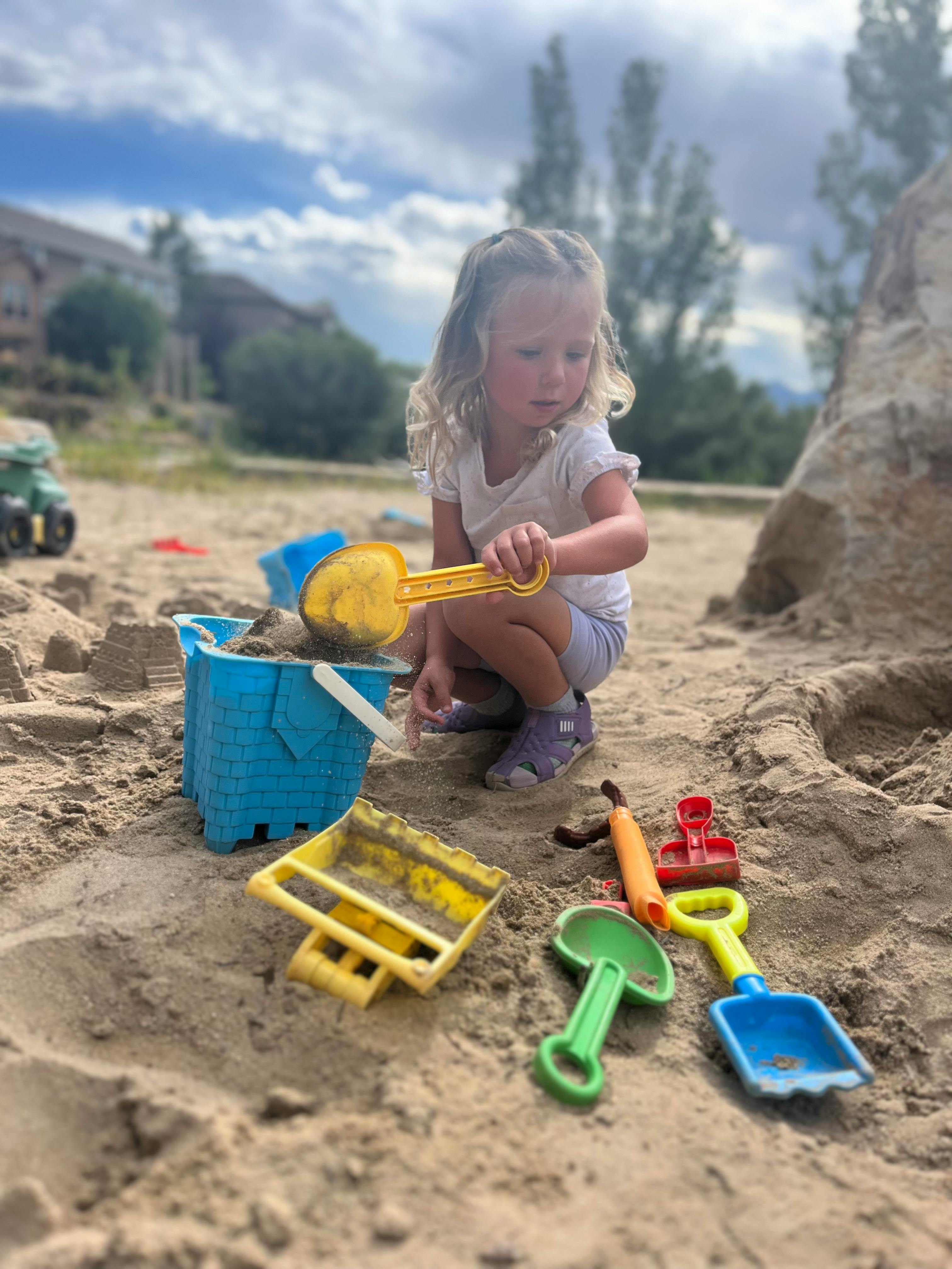 Child playing in sand with a shovel and bucket
