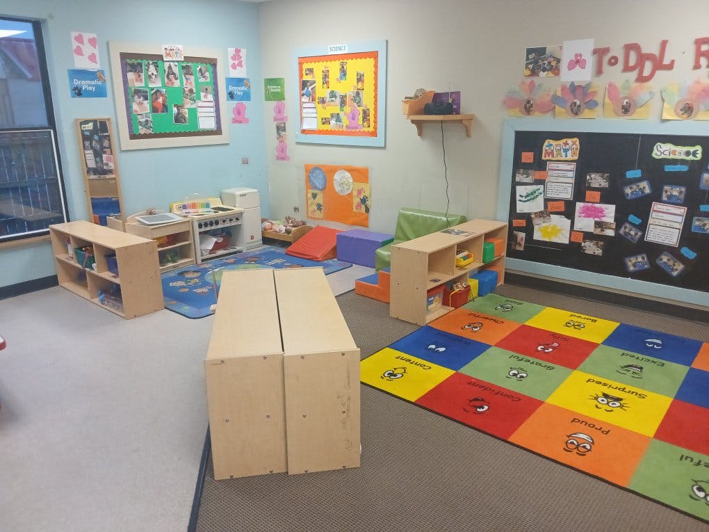 Children's classroom with colorful rug, play kitchen, and educational posters