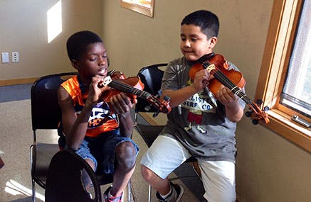 Two children playing violins