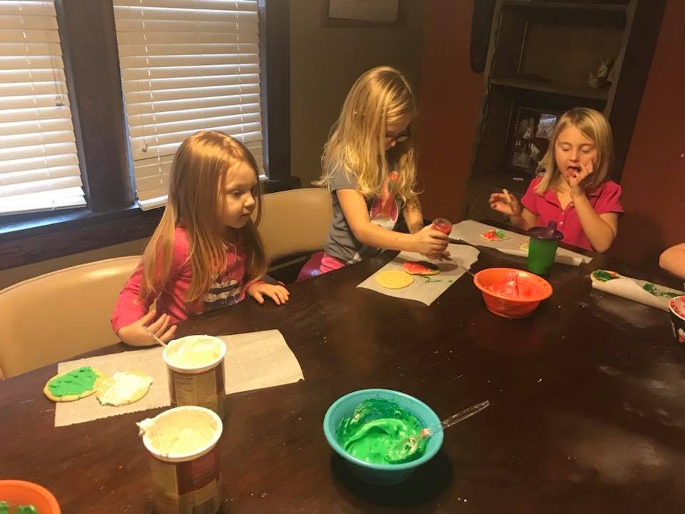 Three children decorating cookies at a table