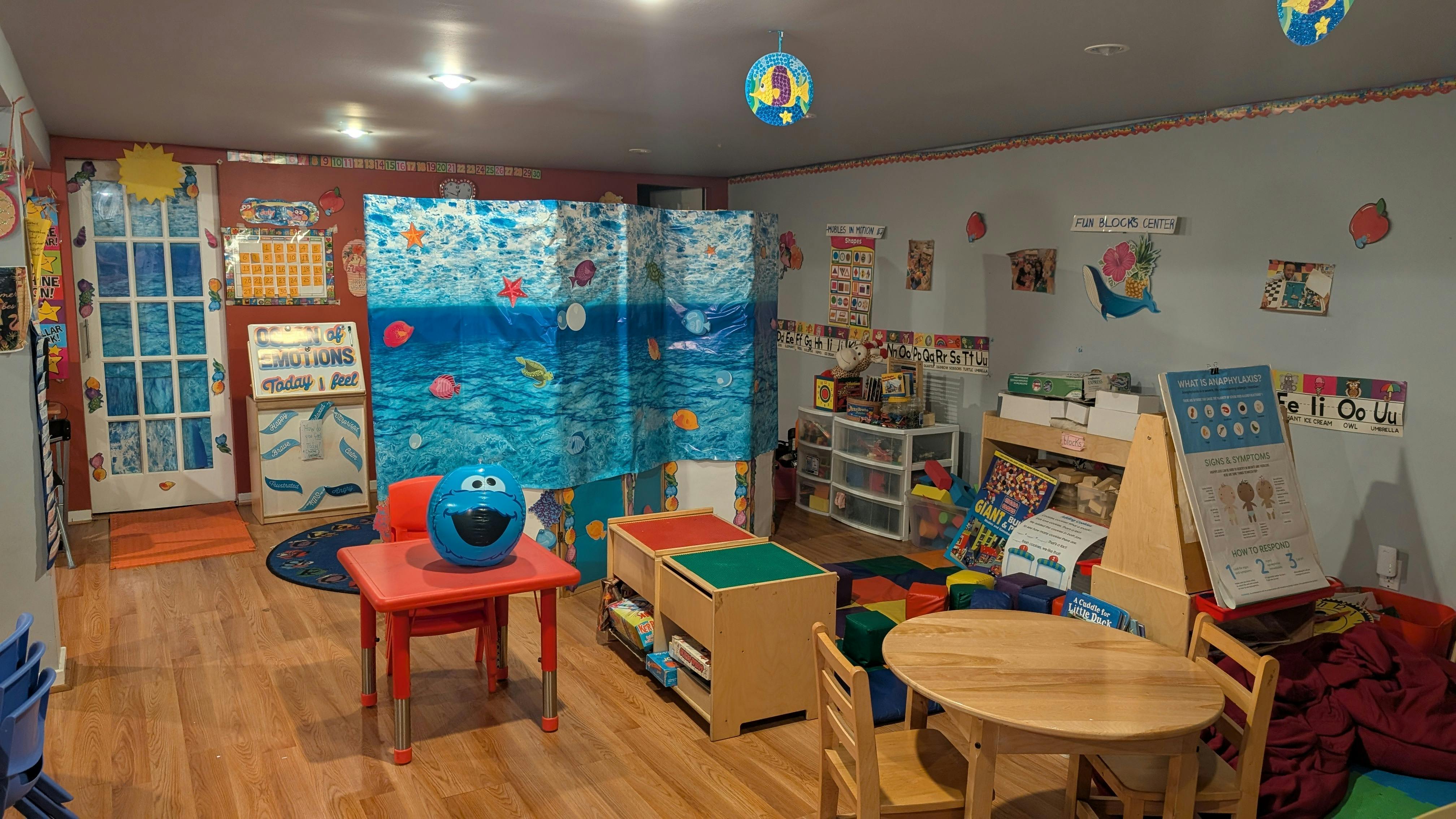 Playroom with small tables and chairs, storage units, and a blue divider