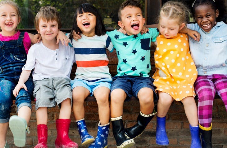 Six children sitting together, some smiling and some laughing